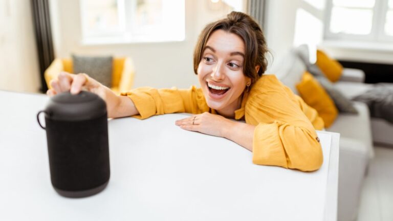 Woman in a mustard sweater asking a voice speaking device