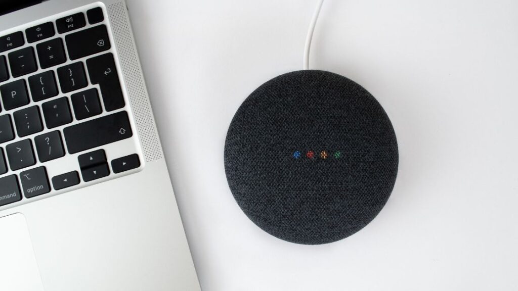 Google Home Assistant beside a Macbook Pro